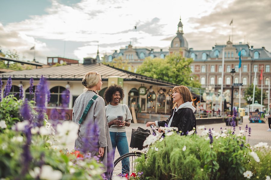 Tre kvinnor står på torget i Sundsvall och pratar med varandra.