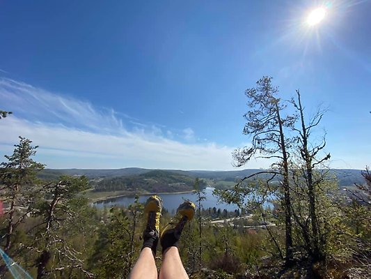 Alttext: En person lyfter sin fötter i skyn, en sjö syns längre bort en solig dag Fotograf: Katrin Wikström Bildtext: -