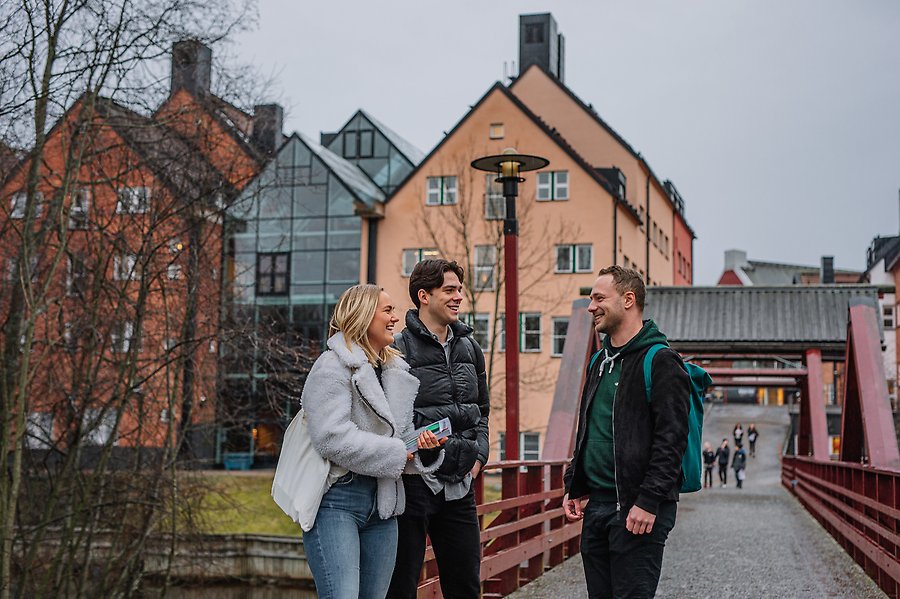 Tre studenter står vid Mittuniversitetets campus vid Selångersån.